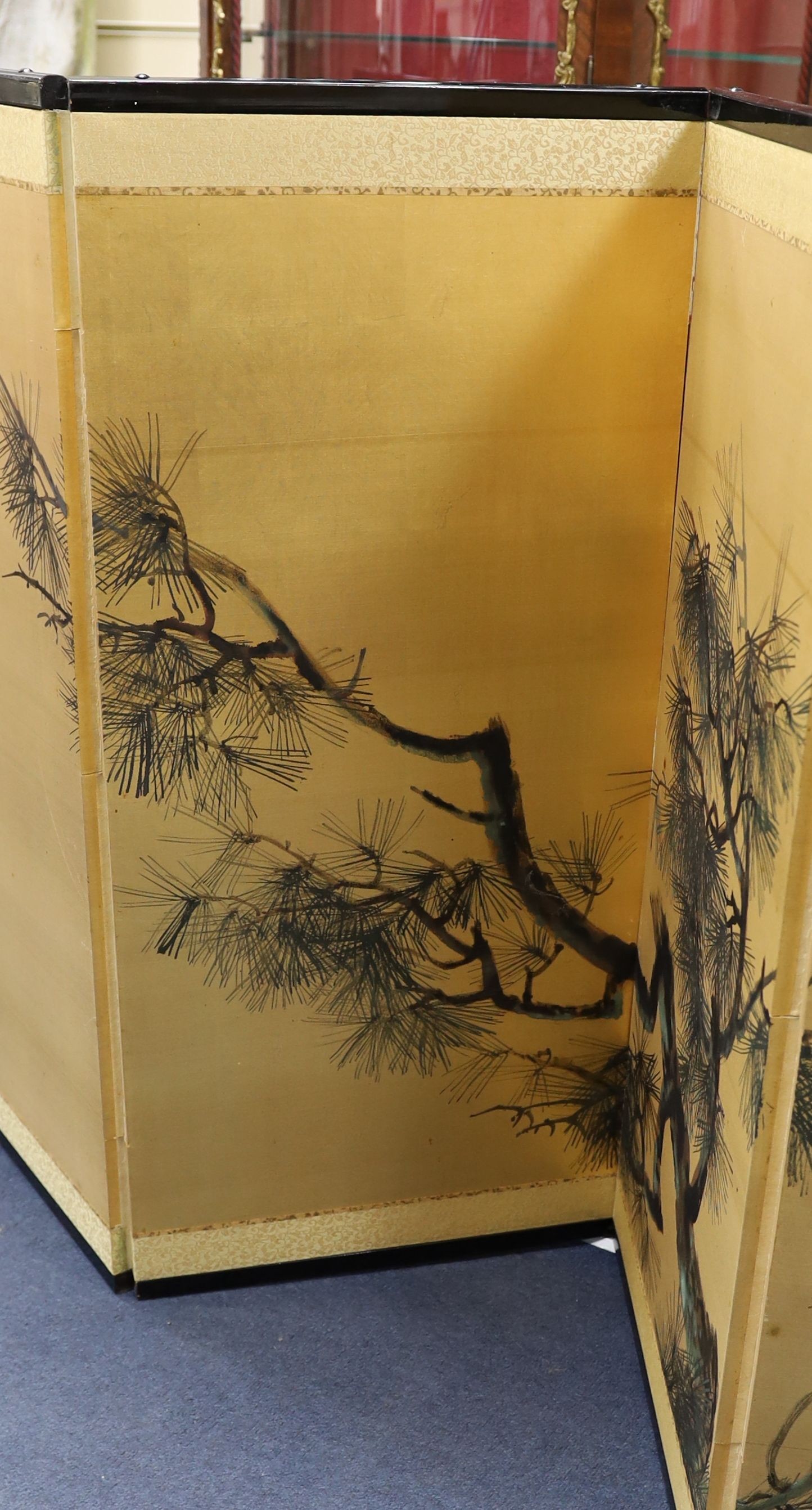 A Japanese gilt screen decorated with pine branches together with a Chinese rectangular wall mirror and a low table.